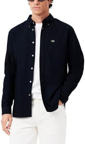 Close-up of the Lacoste crocodile logo embroidered on the chest of a navy blue Oxford fabric shirt.